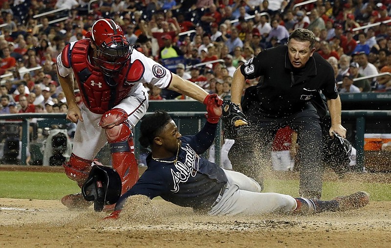 The Atlanta Braves' Ozzie Albies is safe at home as Washington Nationals catcher Matt Wieters can't make the tag in time, with home plate umpire Greg Gibson watching, during the seventh inning of Wednesday night's game in Washington.