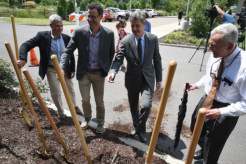 Evergreen Real Estate developers Aaron White, left, and Hunter Connelly approach shovels with Chattanooga Mayor Andy Berke and businessman Grant Law on the site of the West M.L. King Boulevard extension Thursday, Aug. 9, 2018.