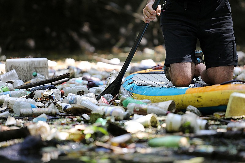 Staff photo by Erin O. Smith / 
Randy Whorton, director of Wild Trails, paddles through a section of Chattanooga Creek with a thick layer of trash covering the surface Wednesday, August 8, 2018 in Chattanooga, Tennessee. Single-use plastic, basketballs, shoes, tires and a 55-gallon drum are just a few of the items that littler the creek.