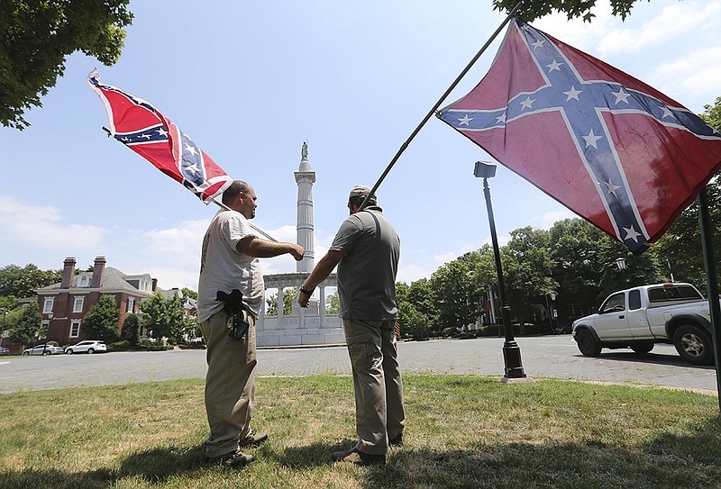 FILE - In this Thursday, June 25, 2015 file photo, activists hold Confederate flags near the monument for Confederate President Jefferson Davis on Monument Avenue in Richmond, Va. 