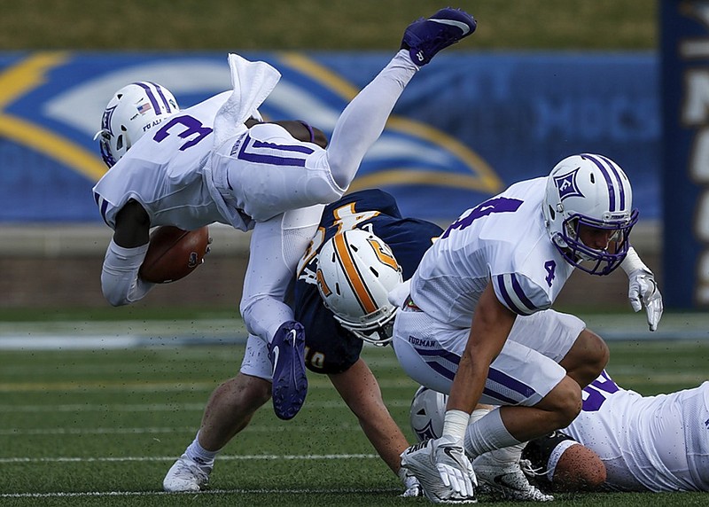 Furman tailback Darius Morehead goes airborne over UTC linebacker Marshall Cooper during a game at Finley Stadium last October. Cooper is among the UTC players who have been impressive during preseason practices so far.