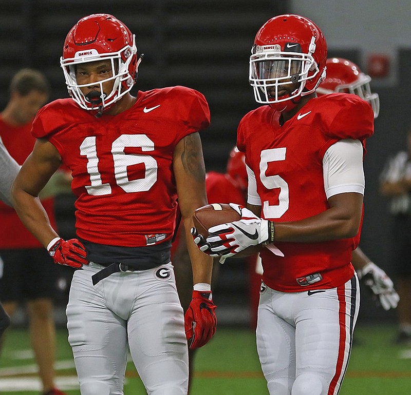 New Georgia receiver Demetris Robertson (16), a transfer from the University of California, visits with Bulldogs senior receiver Terry Godwin during practice last Tuesday.