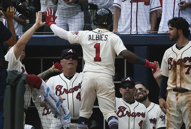 Atlanta's Ozzie Albies is congratulated as he returns to the Braves' dugout after hitting a tiebreaking home run during the seventh inning of Sunday's game against the Milwaukee Brewers.