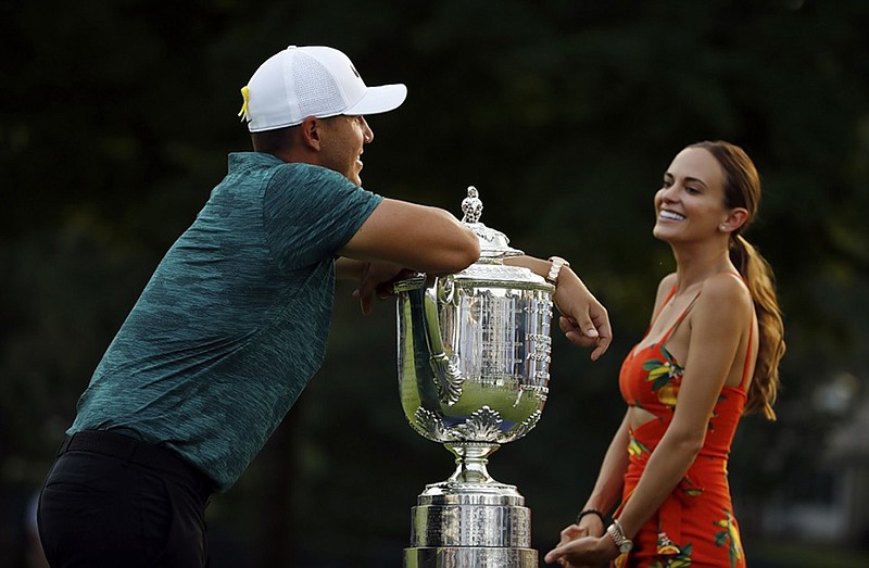 Brooks Koepka leans on the Wanamaker Trophy as he talks with his girlfriend, Jena Sims, after winning the PGA Championship on Sunday at Bellerive Country Club in St. Louis.