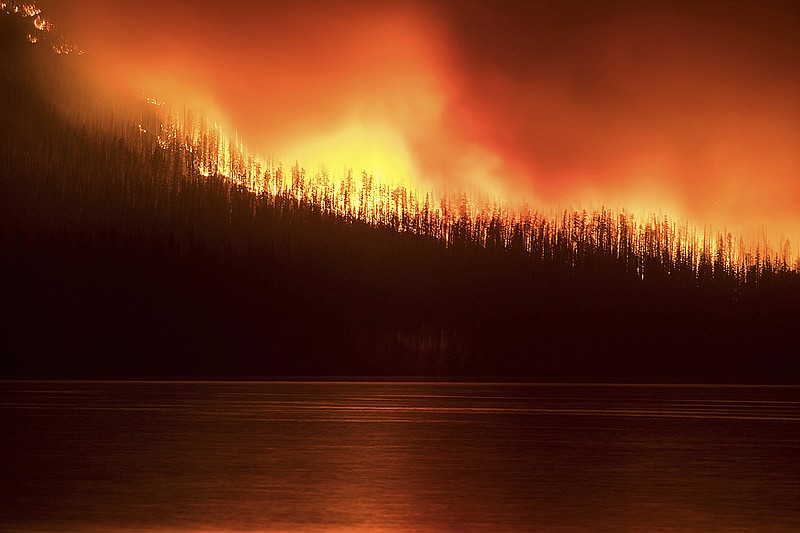 In this photo taken Sunday, Aug. 12, 2018, a fire burns next to Lake McDonald in Glacier National Park in northwest Montana.