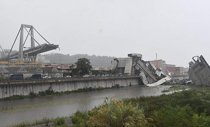 A view of the collapsed Morandi highway bridge in Genoa, northern Italy, Tuesday, Aug. 14, 2018. A large section of the bridge collapsed over an industrial area in the Italian city of Genova during a sudden and violent storm, leaving vehicles crushed in rubble below. (Luca Zennaro/ANSA via AP)