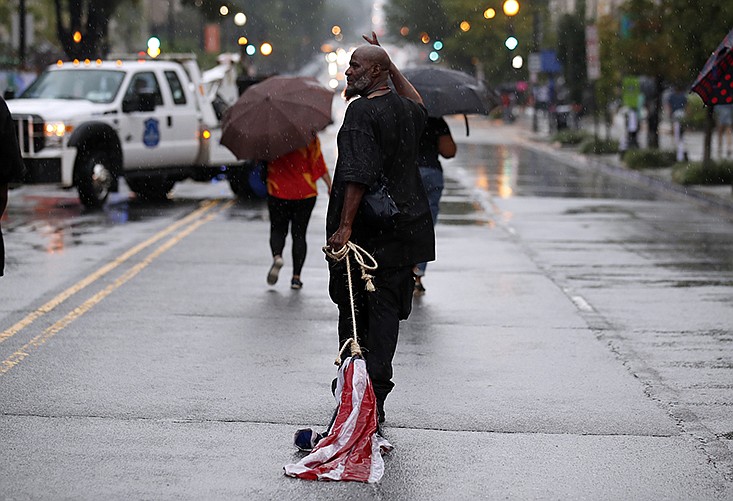 A protestor drags an American flag in the rain as he departs after protests on the one year anniversary of Charlottesville's Unite the Right rally, Sunday, Aug. 12, 2018, in Washington. (AP Photo/Alex Brandon)