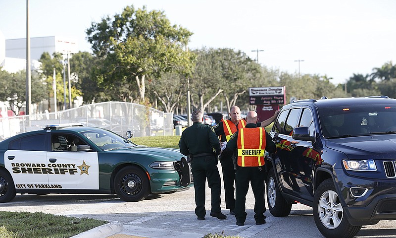 Broward County Sheriff's deputies stand outside Marjory Stoneman Douglas High School, Wednesday, Aug. 15, 2018, in Parkland, Fla. Students at the school returned Wednesday, to a more secure campus as they began their first new school year since a gunman killed 17 people in the freshman building. (AP Photo/Wilfredo Lee)