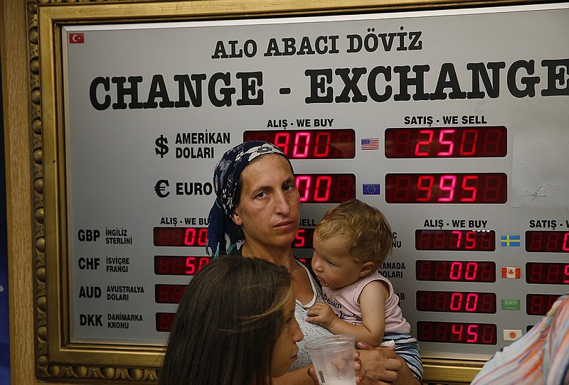 People wait at a currency exchange shop in Istanbul, Wednesday, Aug. 15, 2018. The Turkish lira has nosedived in value in the past week, but some Turks are reacting with defiance to their plunging currency and an escalating trade and political dispute with the United States. (AP Photo/Lefteris Pitarakis)