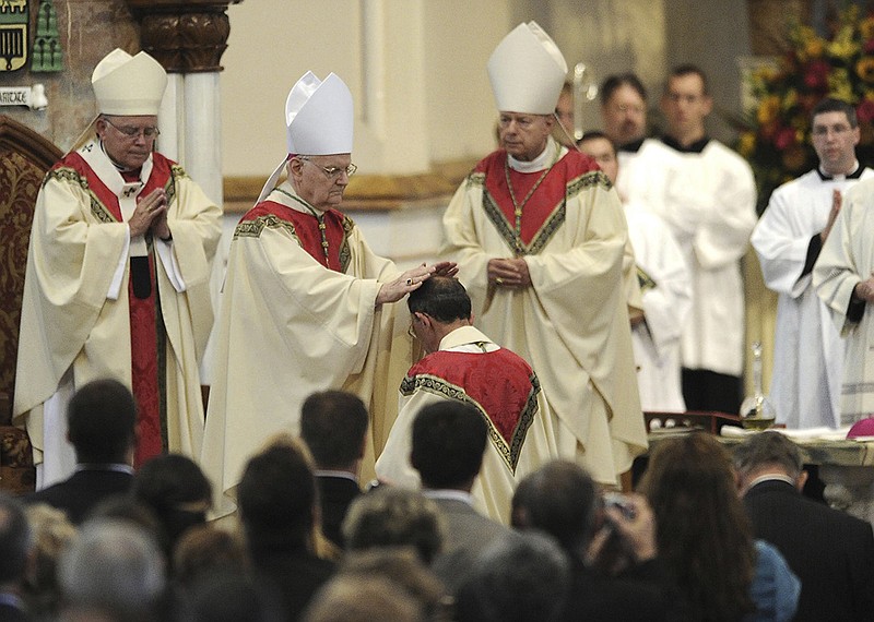 FILE – In this Oct. 1, 2012, file photo, the Most Rev. Donald Trautman, second from left, retiring bishop of Erie, Pa., prays and lays his hands on the head of Monsignor Lawrence T. Persico, kneeling, the bishop-elect of Erie, Pa., during Persico's rite of ordination at St. Peter Cathedral in Erie, Pa. 