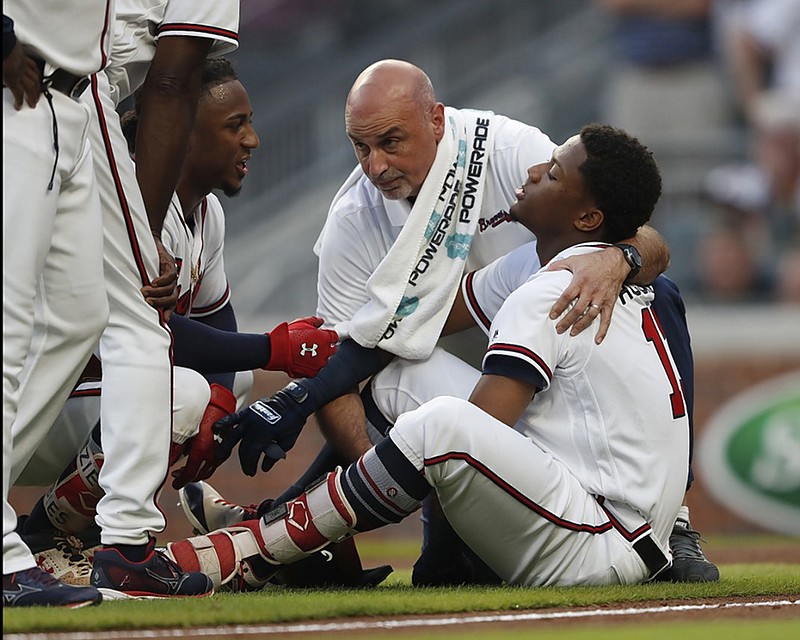 The Atlanta Braves' Ronald Acuna Jr. (13) is tended to by a member of the training staff as teammate Ozzie Albies talks to him after Acuna was hit by a pitch from Miami Marlins starting pitcher Jose Urena during the first inning Wednesday night in Atlanta.