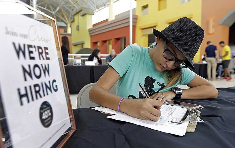 Job seeker Alejandra Bastidas fills out an application at a job fair, Tuesday, Oct. 3, 2017, at Dolphin Mall in Sweetwater, Fla. The shopping center hosted a job fair in preparation for the approaching busy holiday retail season. (AP Photo/Alan Diaz)