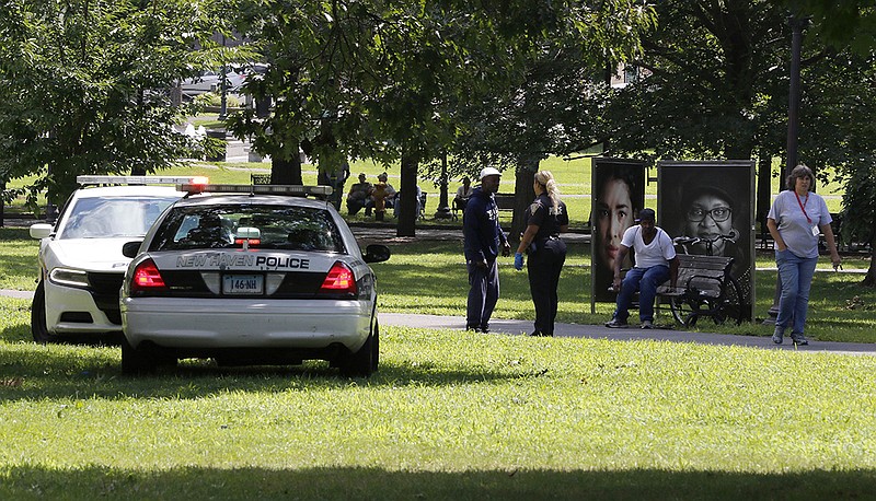 A police officer speaks to a man walking on New Haven Green, Wednesday, Aug. 15, 2018, in New Haven, Conn. A city official said more than a dozen people fell ill from suspected drug overdoses on the green and were taken to local hospitals. (AP Photo/Bill Sikes)

