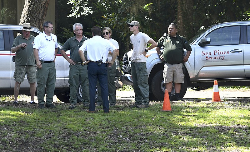 Law enforcement with Sea Pines Security, S.C. Department of Natural Resources and the Beaufort County Sheriff's Office stand near where authorities say Cassandra Cline was dragged into a lagoon by an alligator and killed while trying to save her dog on Monday, Aug. 20, 2018, on Hilton Head Island, S.C. Cline was walking the dog along a residential area of Sea Pines Resort when she was attacked, state and local officials said. (Drew Martin/The Island Packet via AP)

