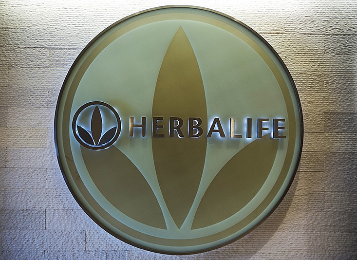 FILE- This May 11, 2016, file photo, shows the Herbalife logo at the company's corporate office, in Los Angeles. Some distributors who claim they were duped by Herbalife's promises they'd get rich selling health and personal care products are suing the company for as much as $1 billion in damages. (AP Photo/Damian Dovarganes, File)