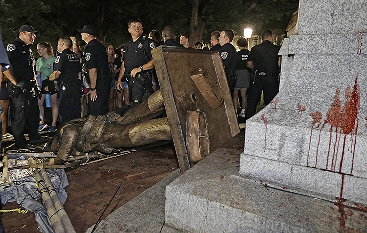 Police stand guard after the confederate statue known as Silent Sam was toppled by protesters on campus at the University of North Carolina in Chapel Hill, N.C., Monday, Aug. 20, 2018. (AP Photo/Gerry Broome)


