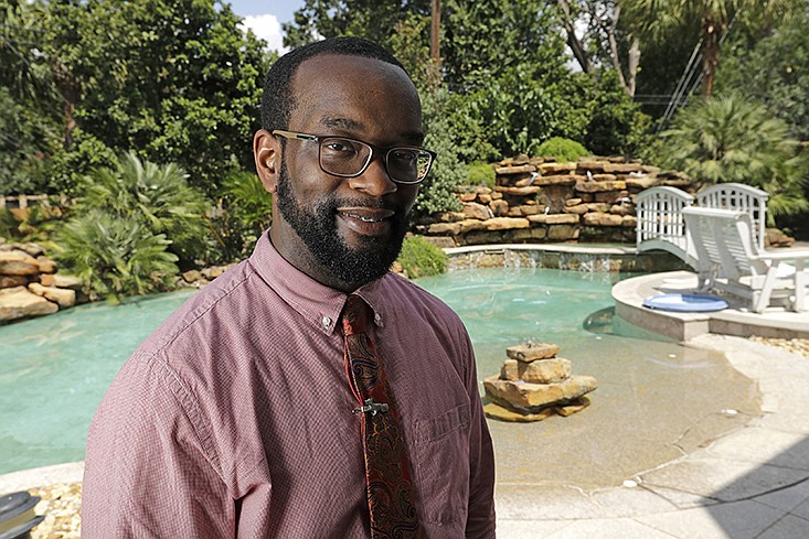 In this Aug. 17, 2018, photo Marcus Harris poses at his home in Spring, Texas. Harris, a 34-year-old physician in the Houston area who started investing about five years ago. "It's going to sound terrible, but I'm actually looking forward to the next downturn," he said of the opportunity to buy stocks at a lower price. "I know it's an overbought position right now, and I'm just sitting on my hands saying, 'I can't wait.' Hopefully it will go to half the price, and I can gobble up a lot of it." (AP Photo/David J. Phillip)