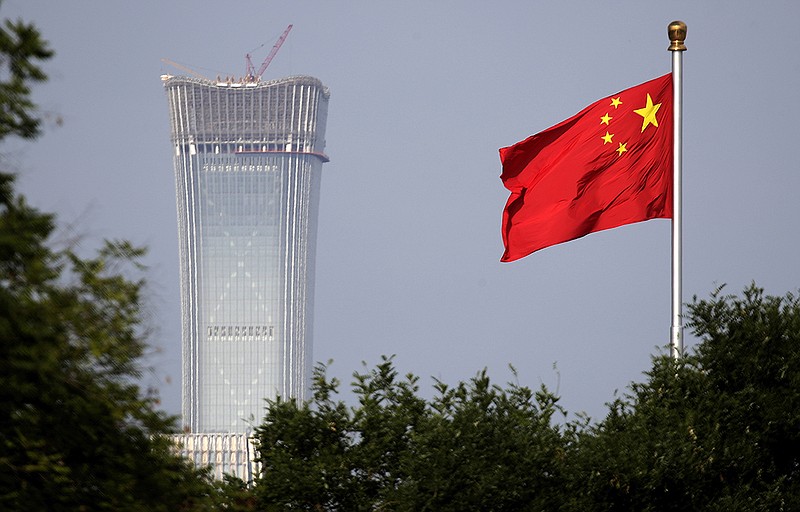 A Chinese national flag at Tiananmen Square flutters against the capital city's tallest skyscraper, China Zun Tower, under construction at the Central Business District in Beijing. (AP Photo/Andy Wong, File)