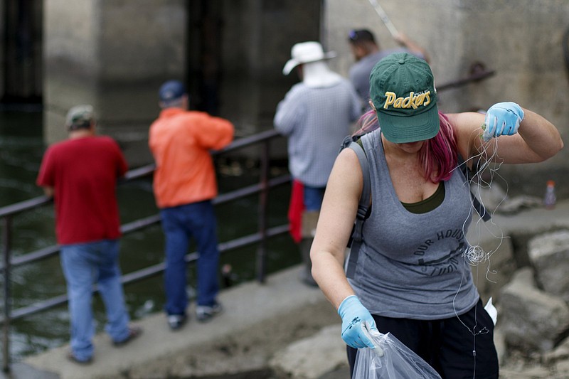 A quartet of fishermen work the Chickamauga Dam as Kim Turner picks up littered fishing line along the Tennessee Riverwalk on Saturday, Aug. 25. The cleanup was organized by GreenSteps and The Wilderness Society.