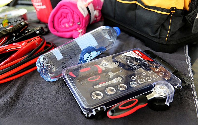 What should you have in your car in case of emergency? The list includes, clockwise from left, jumper cables, a brightly colored blanket, water and a tool kit. These items were photographed at S&S Auto Repair on Airpark Drive.