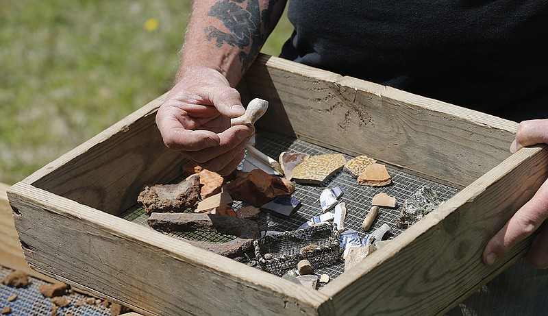 In this April 10, 2018 photo, a Jamestown Rediscovery Foundation archeologist shows artifacts and discusses what they know about one of the first enslaved Africans to live in English North America in Jamestown, Va. A new tour at the site of the historic Jamestown colony encourages visitors to consider the beginnings of American slavery. It's part of a broader national effort to reckon with slavery's legacy. (AP Photo/Steve Helber)