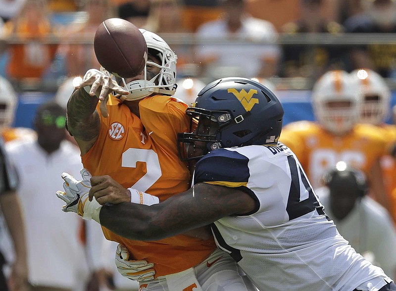 Tennessee's Jarrett Guarantano loses the ball as he is hit by West Virginia's Kenny Bigelow Jr. in the first half of Saturday's game in Charlotte, N.C. The play was ruled an incomplete pass.