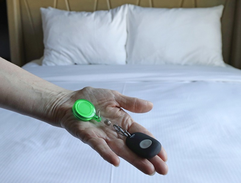 In this Wednesday, Sept. 5, 2018, photo Rani Accettola, a housekeeper at the Embassy Suites by Hilton hotel in Seattle's Pioneer Square neighborhood, poses for a photo while holding a device that lets her push a button and summon help if she is in a threatening situation while working in Seattle. (AP Photo/Ted S. Warren)