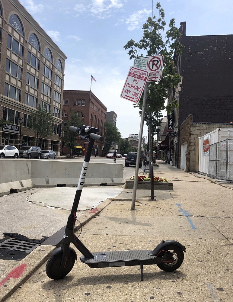 In this photo taken Thursday, July 12, 2018, a dockless scooter sits on a sidewalk in downtown Milwaukee. Cities across the U.S. are grappling with how to deal with electric scooters that have begun appearing in sidewalks overnight without any regulations. (AP Photo/Carrie Antlfinger)