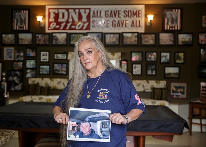 Staff photo by Doug Strickland / 
Faith Smith poses with a photograph of her husband, former New York Fire Department firefighter Michael Smith, Jr., in her home on Tuesday, Sept. 11, 2018, in Harrison, Tenn. Firefighter Smith died in 2015 from complications related to his work at Ground Zero in the aftermath of the 9/11 terrorist attacks in New York City.