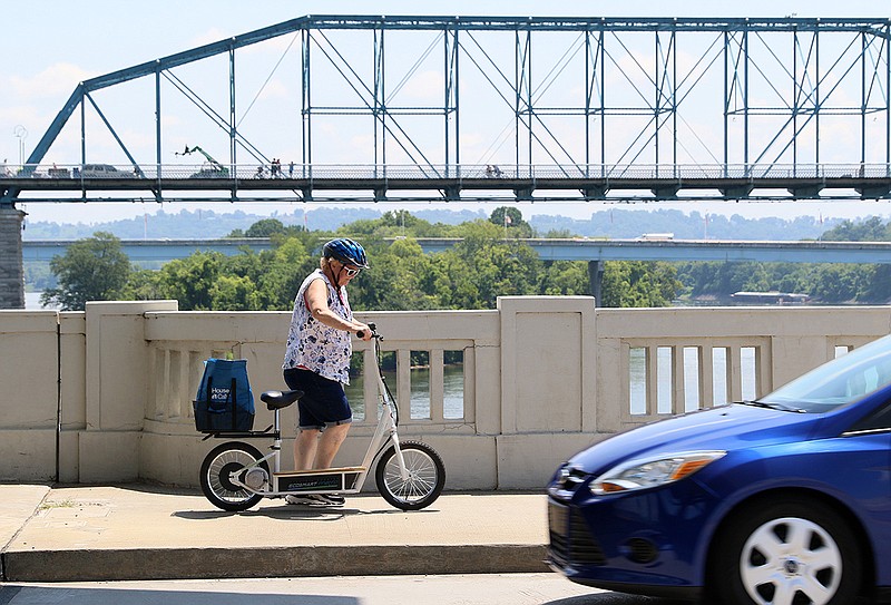 A pedestrian walks her electric scooter across a portion of Market Street Bridge before hopping back on to drive through downtown Chattanooga, Tenn., Tuesday, July 18, 2017.