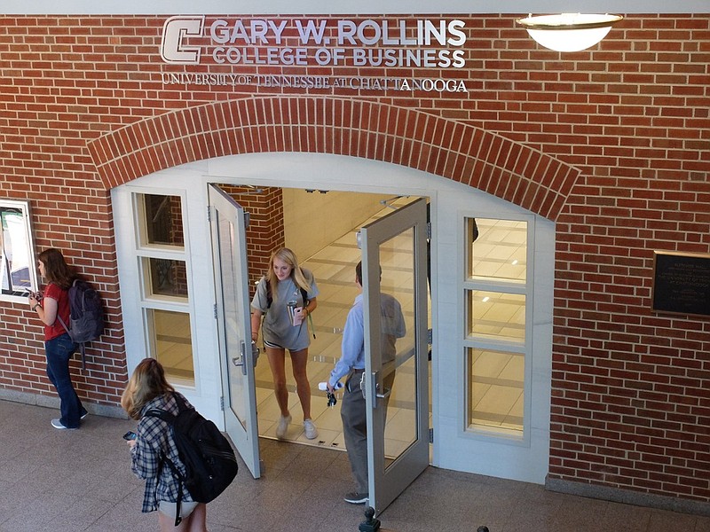 The name of the Gary W. Rollins College of Business is already visible above as students pass beneath as the naming celebration takes place outside on the lawn Thursday.  Rollins donated a $40-million gift to the school.