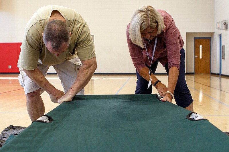 Staff photo by C.B. Schmelter / 
Volunteer Chuck Cruthirds, left, and April Martin, with American Red Cross Disaster Cycle Services, help set up a cot in the gym at the Brainerd Youth and Family Development Center on Thursday, Sept. 13, 2018 in Chattanooga, Tenn. The Hamilton County Office of Emergency Management, American Red Cross and other organizations are joining to open and operate a shelter at the Brainerd Youth & Family Development Center for coastal residents fleeing Hurricane Florence, according to a news release.