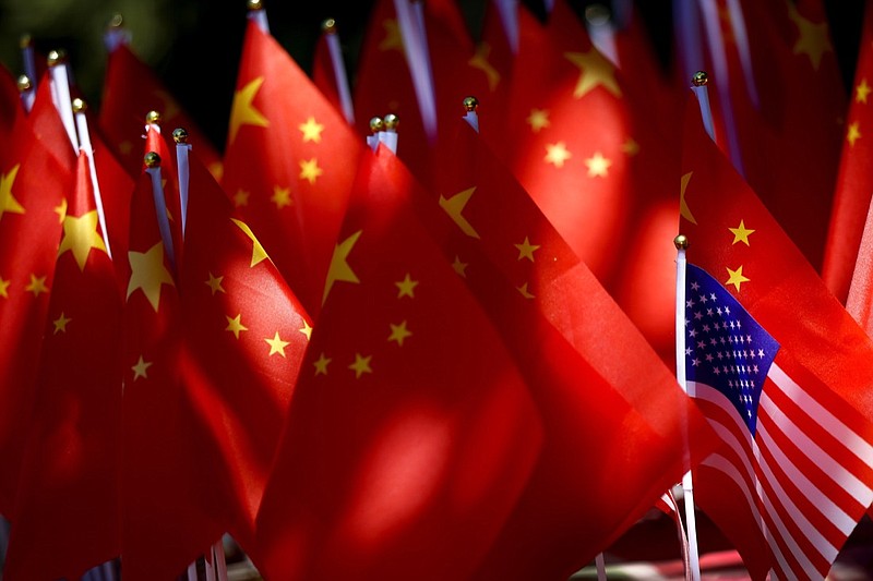 In this Sunday, Sept. 16, 2018, photo, an American flag is displayed together with Chinese flags on top of a trishaw in Beijing. Chinese news reports have quoted a former finance minister as saying Beijing can disrupt American companies' operations by imposing "export controls" if it needs more leverage in its mounting tariff dispute with Washington. (AP Photo/Andy Wong)
