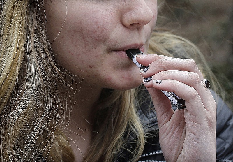 In this April 11, 2018, file photo, an unidentified 15-year-old high school student uses a vaping device near the school's campus in Cambridge, Mass. A school-based survey shows nearly 1 in 11 U.S. students have used marijuana in electronic cigarettes, heightening concern about the new popularity of vaping among teens. E-cigarettes typically contain nicotine, but results published Monday, Sept. 17, mean a little more than 2 million middle and high school students have used the devices to get high. (AP Photo/Steven Senne, File)