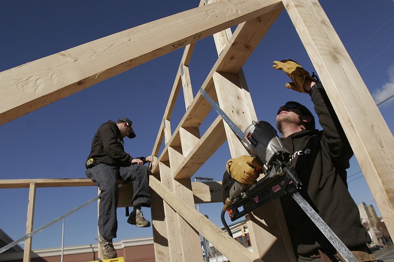 In this 2009 staff file photo, Collier Construction superintendent Bryan King holds part of the framework steady on a Habitat for Humanity house while project superintendent Dustin Douglass uses a nail gun to secure a brace for it. 