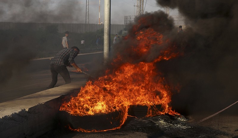Protesters burn tires during a protest at the entrance of Erez border crossing between Gaza and Israel, in the northern Gaza Strip, Tuesday, Sept. 18, 2018. Gaza's Health Ministry says two Palestinians were killed by Israeli fire at a protest near a crossing point between the enclave and Israel. (AP Photo/Adel Hana)