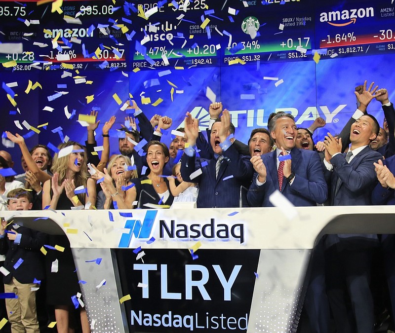 FILE- In this July 19, 2018, file photo Brendan Kennedy, third from right in front, CEO and founder of British Columbia-based Tilray Inc., a major Canadian marijuana grower, leads cheers as confetti falls to celebrate his company's IPO (TLRY) at Nasdaq in New York. Investors are craving marijuana stocks as Canada prepares to legalize pot next month, leading to giant gains for Canada-based companies listed on U.S. exchanges. (AP Photo/Bebeto Matthews, File)


