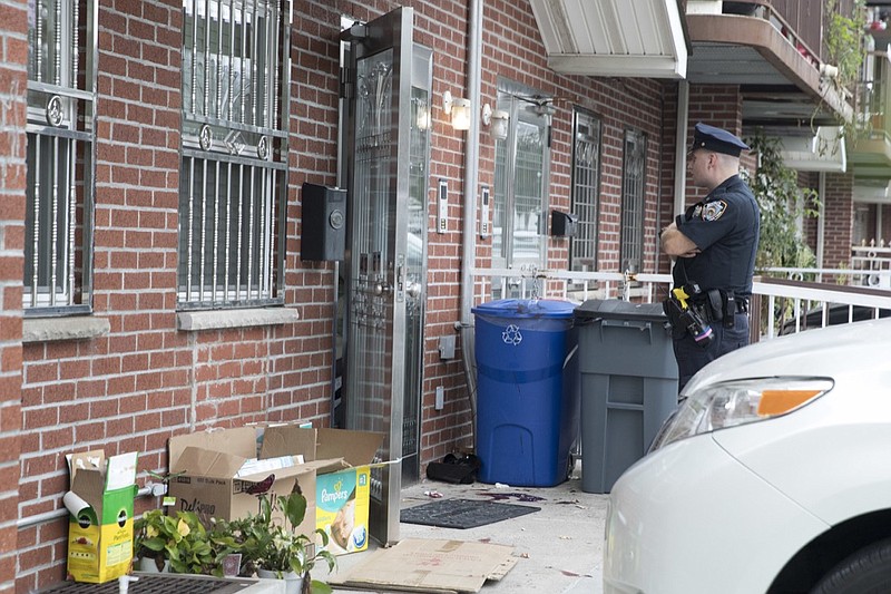 A police officer stands guard at the house were five people were stabbed overnight is seen, Friday, Sept. 21, 2018, in New York. Police say five people, including three infants, were stabbed at an overnight day care center in New York City. (AP Photo/Mary Altaffer)