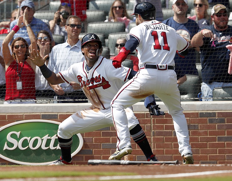 The Atlanta Braves' Ronald Acuna Jr., left, and Ender Inciarte celebrate after scoring on a two-run base hit by Freddie Freeman in the second inning of Saturday's game against the Philadelphia Phillies. Atlanta won 5-3 for its third straight victory against the Phillies and clinched the NL East title with more than a week left in the regular season.