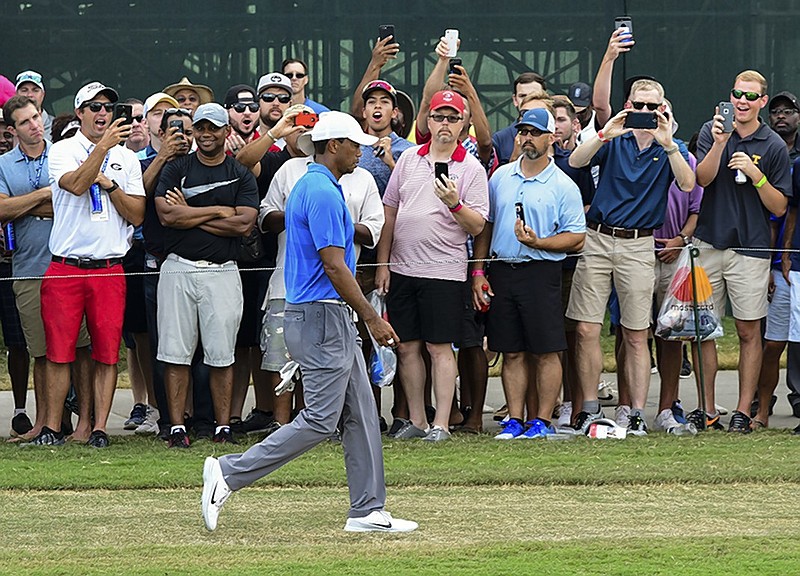 Tiger Woods walks past fans on his way to the 15th green at Atlanta's East Lake Golf Club during the third round of the Tour Championship on Saturday. Woods shot a 5-under-par 65 and held a three-stroke lead entering the final round.