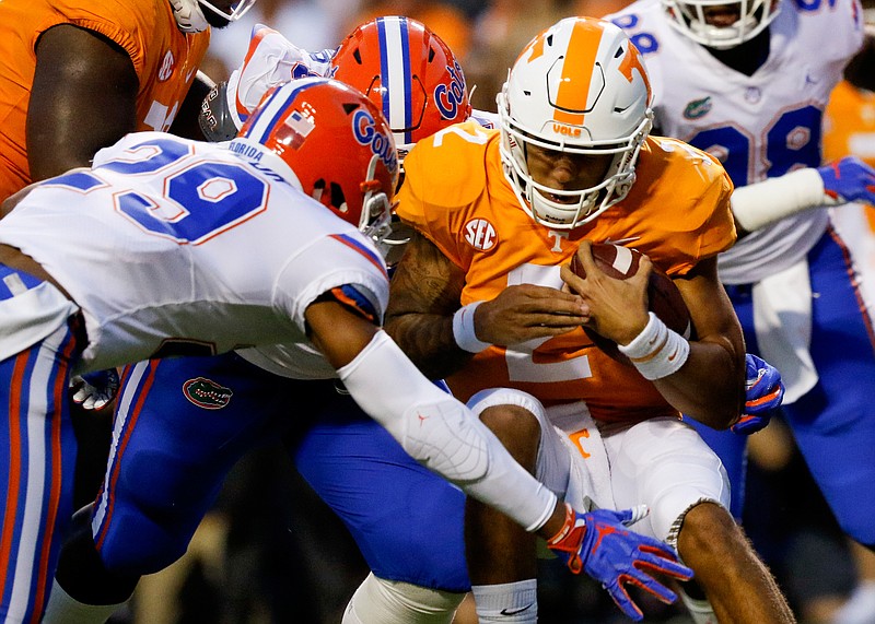 Tennessee quarterback Jarrett Guarantano braces as he is hit by Florida defensive back Jeawon Taylor (29) and defensive lineman Tedarrell Slaton, obscured, during Saturday night's SEC East game at Neyland Stadium in Knoxville.