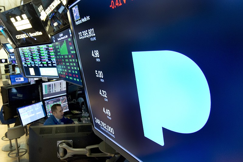 FILE - In this Feb. 22, 2018, file photo, the Pandora logo appears above a trading post on the floor of the New York Stock Exchange. Subscription radio company SiriusXM says it's buying music streaming service Pandora Media Inc. in a stock deal valued at about $3.5 billion that'll allow it to expand its service beyond cars and into homes and other mobile areas. (AP Photo/Richard Drew, File)