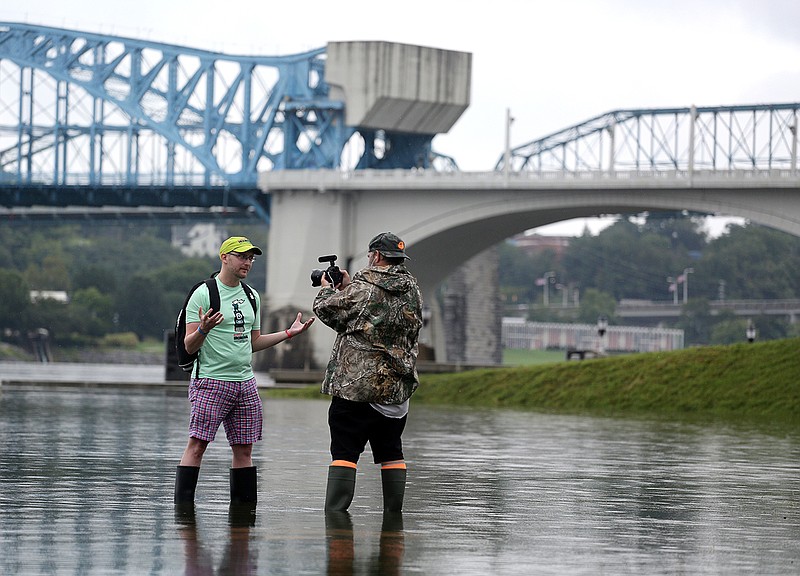 Aaron Pendergraft of Ault, Colorado, comments about the cancelation of the swim portion of the Ironman Chattanooga as he and Ed Burgess, a videographer for Ironman Chattanooga, wade into the water which is much higher than normal during setup for the Ironman Thursday, September 27, 2018, in Chattanooga, Tennessee. Pendergraft said he is a two-time Ironman failure, meaning he didn't complete it in time, and a nine-time Ironman finisher. Ironman athletes will have to forgo the swim portion of the Ironman due to flooding and dangerous conditions on the Tennessee River. (Staff photo by Erin O. Smith)