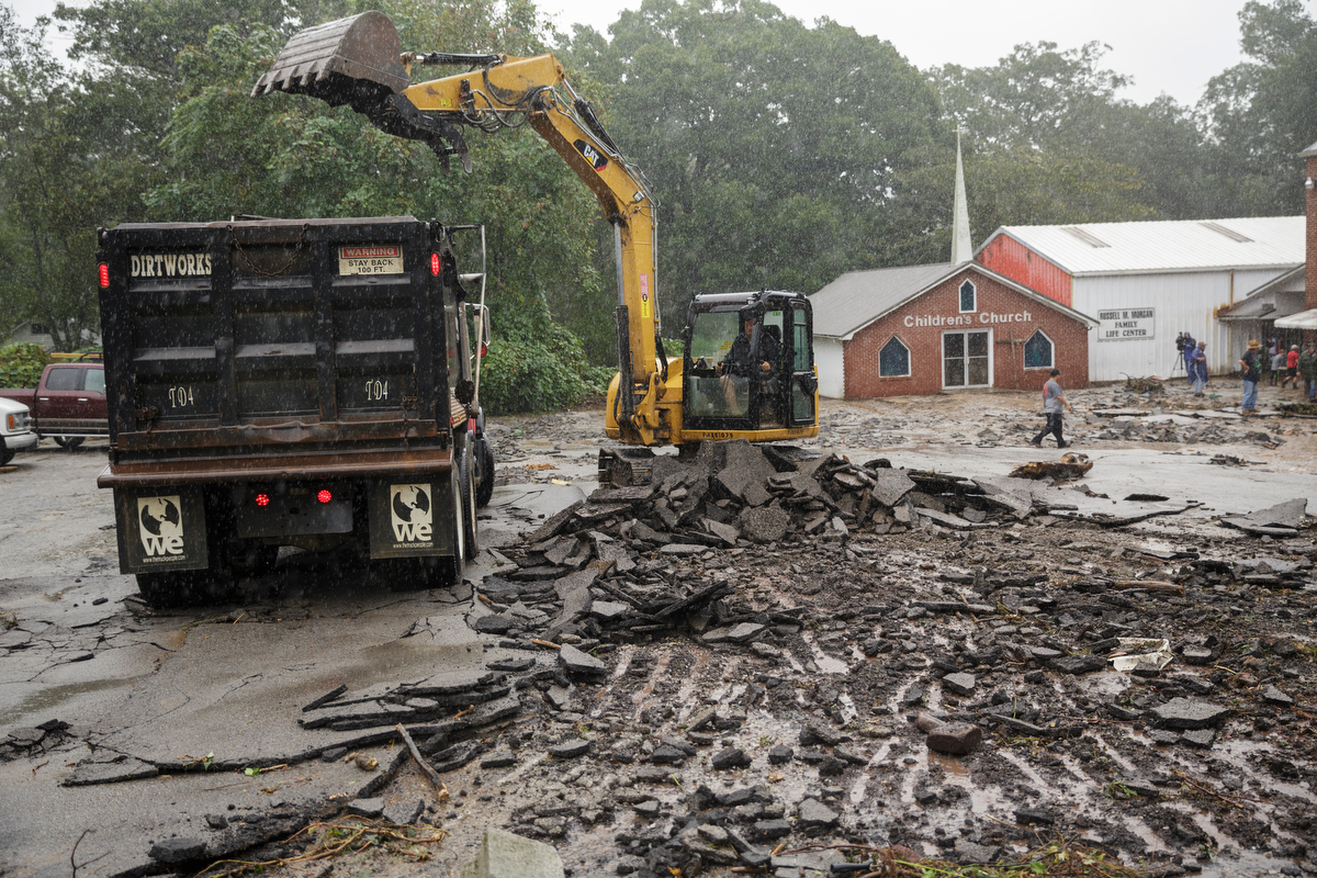 An excavator pulls up the ruined parking lot of Soddy Church of God one day after a deadly flash flood in the Depot Street area on Thursday, Sept. 27, 2018, in Soddy-Daisy, Tenn. Residents, volunteers and business owners returned Thursday following the flooding which killed one person Wednesday.