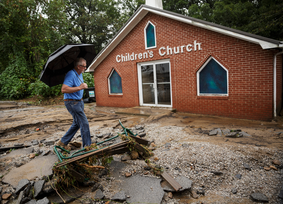 Hugh Carter walks past the damaged parking lot of Soddy Church of God one day after a deadly flash flood in the Depot Street area on Thursday, Sept. 27, 2018, in Soddy-Daisy, Tenn. Residents, volunteers and business owners returned Thursday following the flooding which killed one person Wednesday.