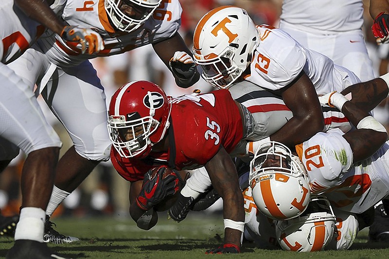 Georgia running back Brian Herrien fights for extra yards through the tackles of Tennessee linebacker Deandre Johnson (13), defensive back Bryce Thompson (20) and linebacker Daniel Bituli, bottom, during Saturday's SEC East matchup at Sanford Stadium in Athens, Ga.