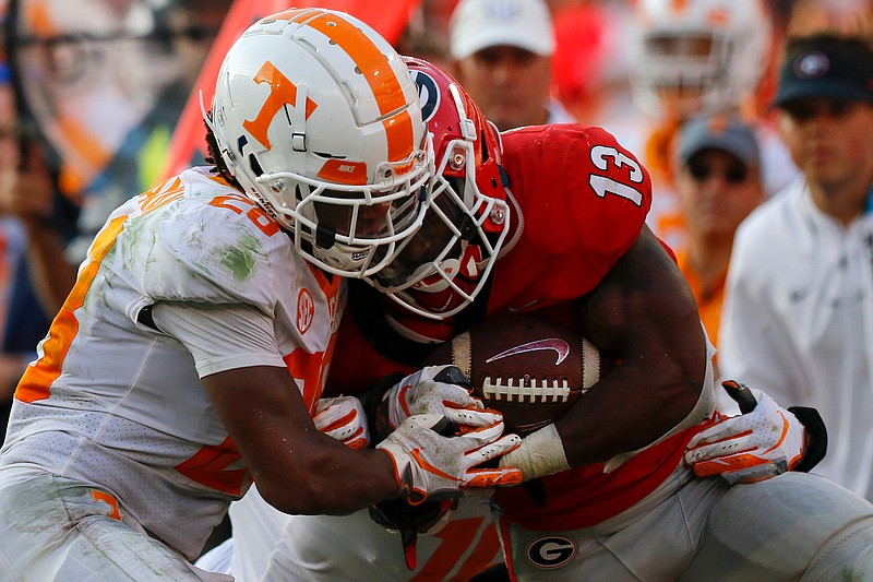 Tennessee defensive back Baylen Buchanan (28) and linebacker Quart'e Sapp, obscured, force Georgia running back Elijah Holyfield out of bounds during their game Sept. 29 in Athens, Ga.