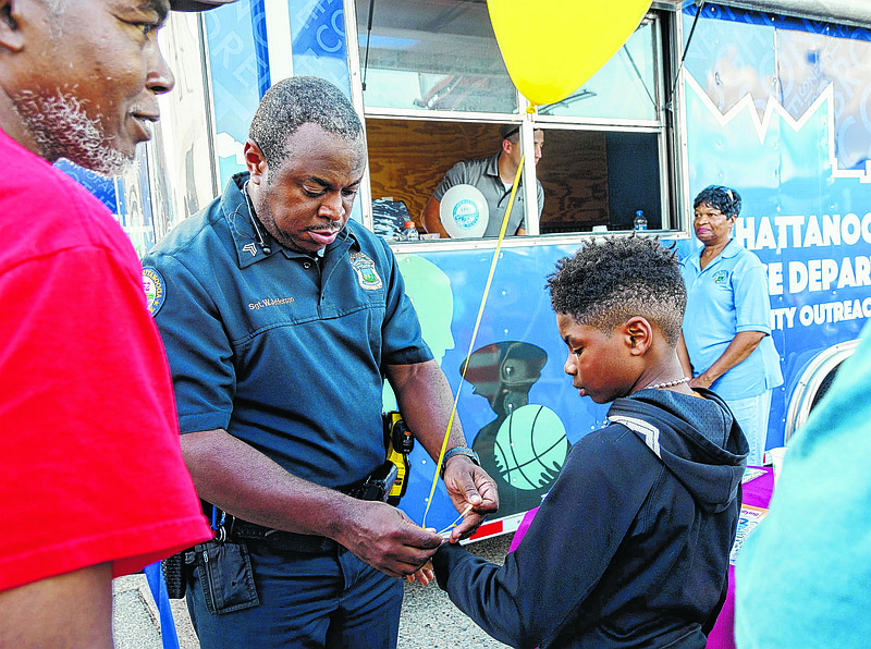 Chattanooga Police Sgt. Wayne Jefferson puts a balloon on Christopher Sheffield Jr.'s wrist during the National Night Out event in St. Elmo. "The safety of our city depends on both law enforcement and citizens working together. National Night Out enhances that cooperation," a release for the local events read.