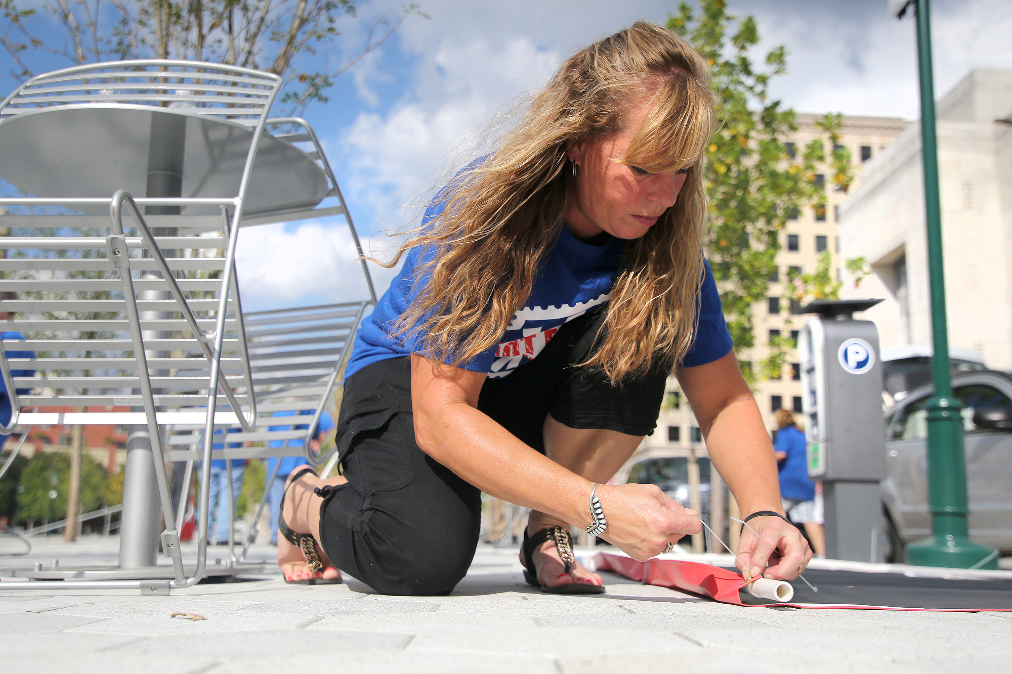 Carole Chubbuck, a member of the American Postal Workers Union, ties a sign to posts Monday, October 8, 2018 at Miller Park in Chattanooga, Tennessee. Chubbuck and about two dozen other stood in the park with signs that read "U.S. Mail Not For Sale."