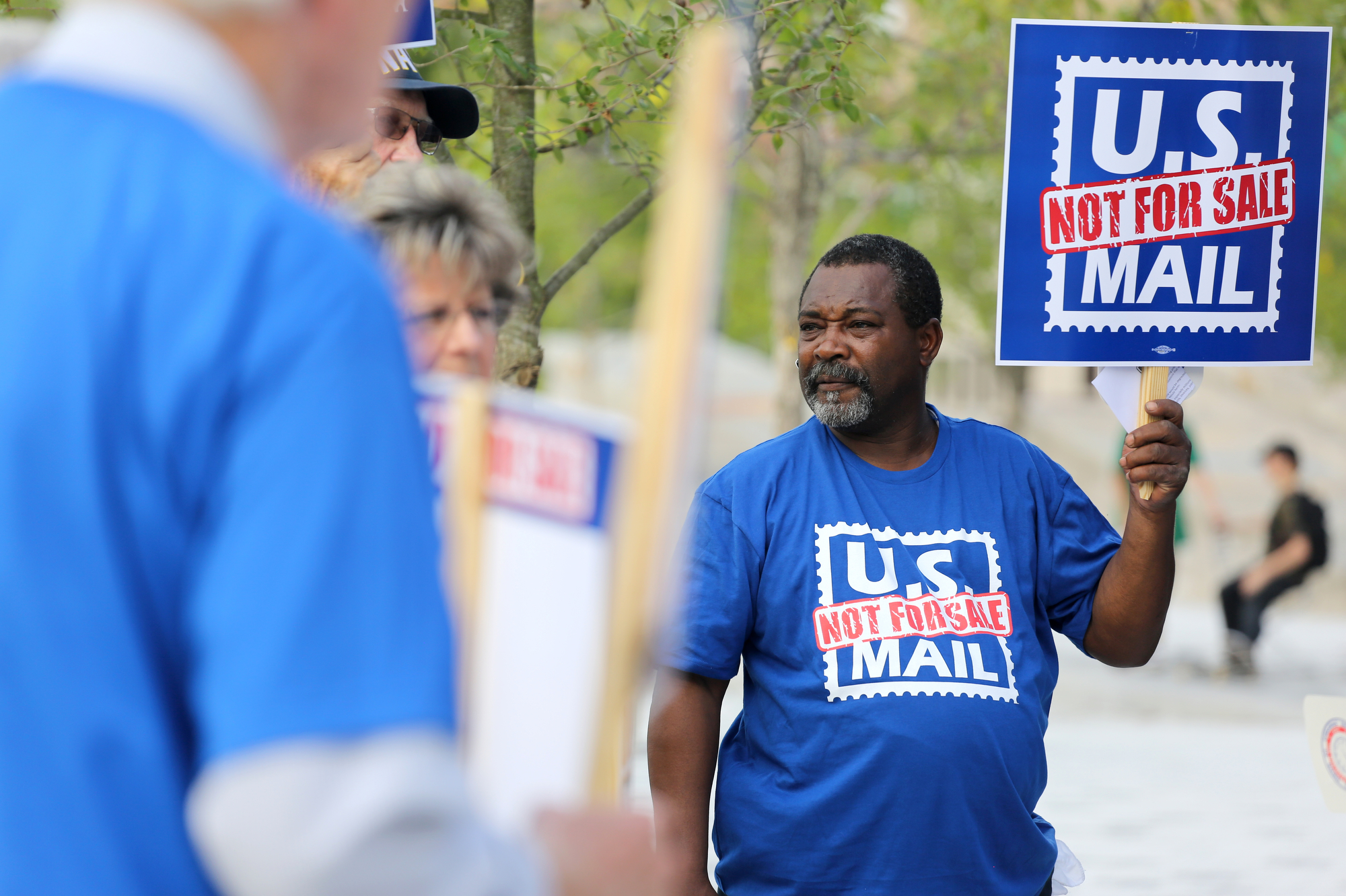 Cedric Neal with the Operating Engineers Local 917 holds up a sign during a protest Monday, October 8, 2018 at Miller Park in Chattanooga, Tennessee. Earlier this year, President Donald Trump said he believes privatizing the U.S. Postal Service would make it operate more efficiently and at lower cost.